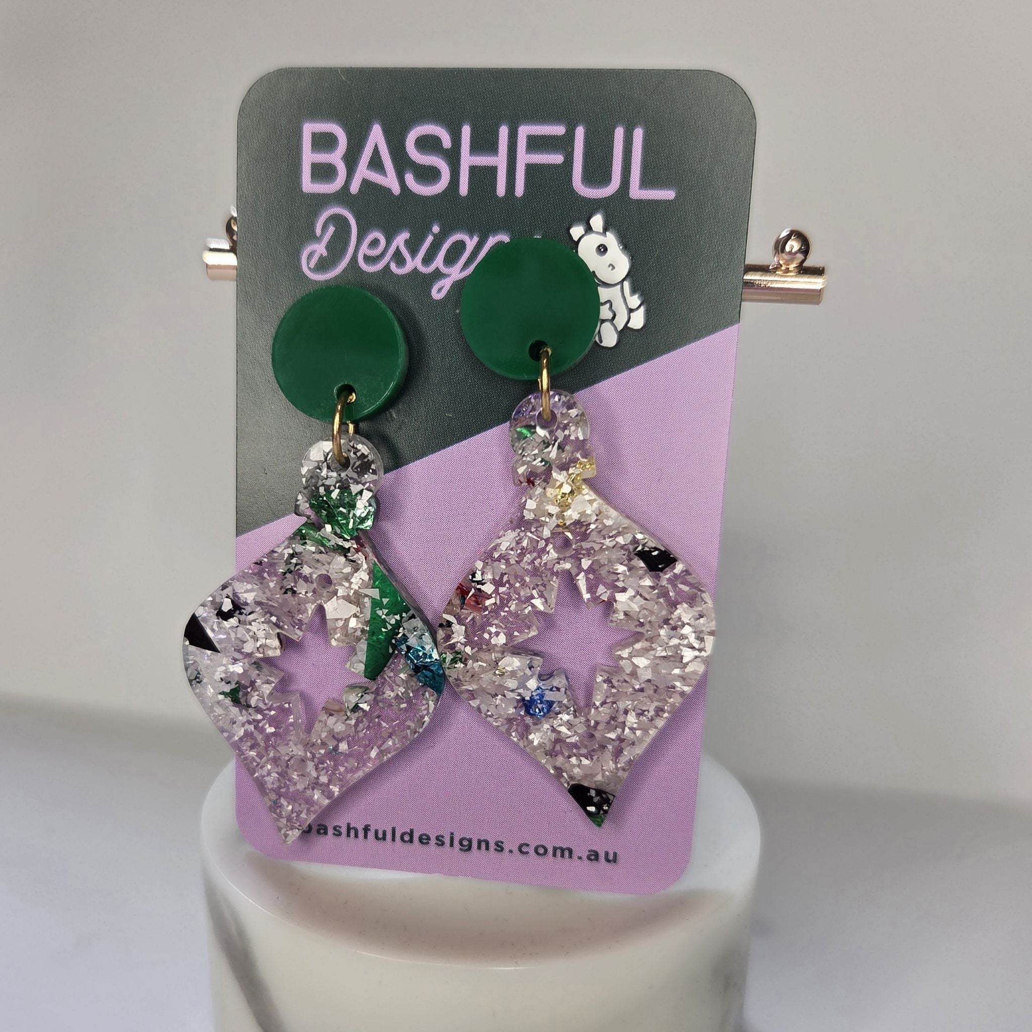 Earrings in the shape of a Christmas Tree bauble.  The earrings begin with a dark green acrylic topper, then flow into a bauble shape in silvery chunky glitter acrylic. 