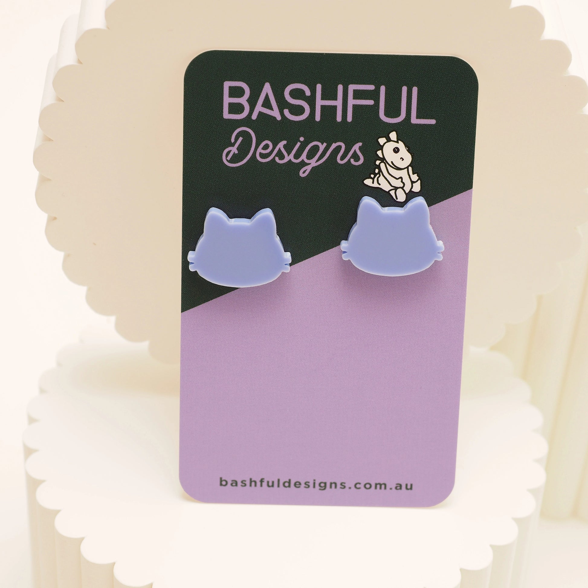 Light blue stud earrings in the shape of a cat, on a 'Bashful Designs' card.