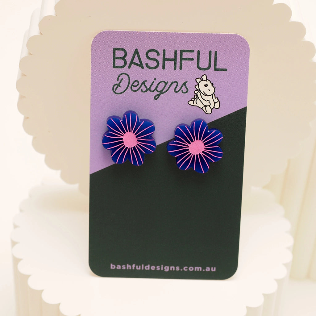 Dark blue and bright pink daisy studs mounted on a branded earring card. These are larger studs and made from hand-painted acrylic.