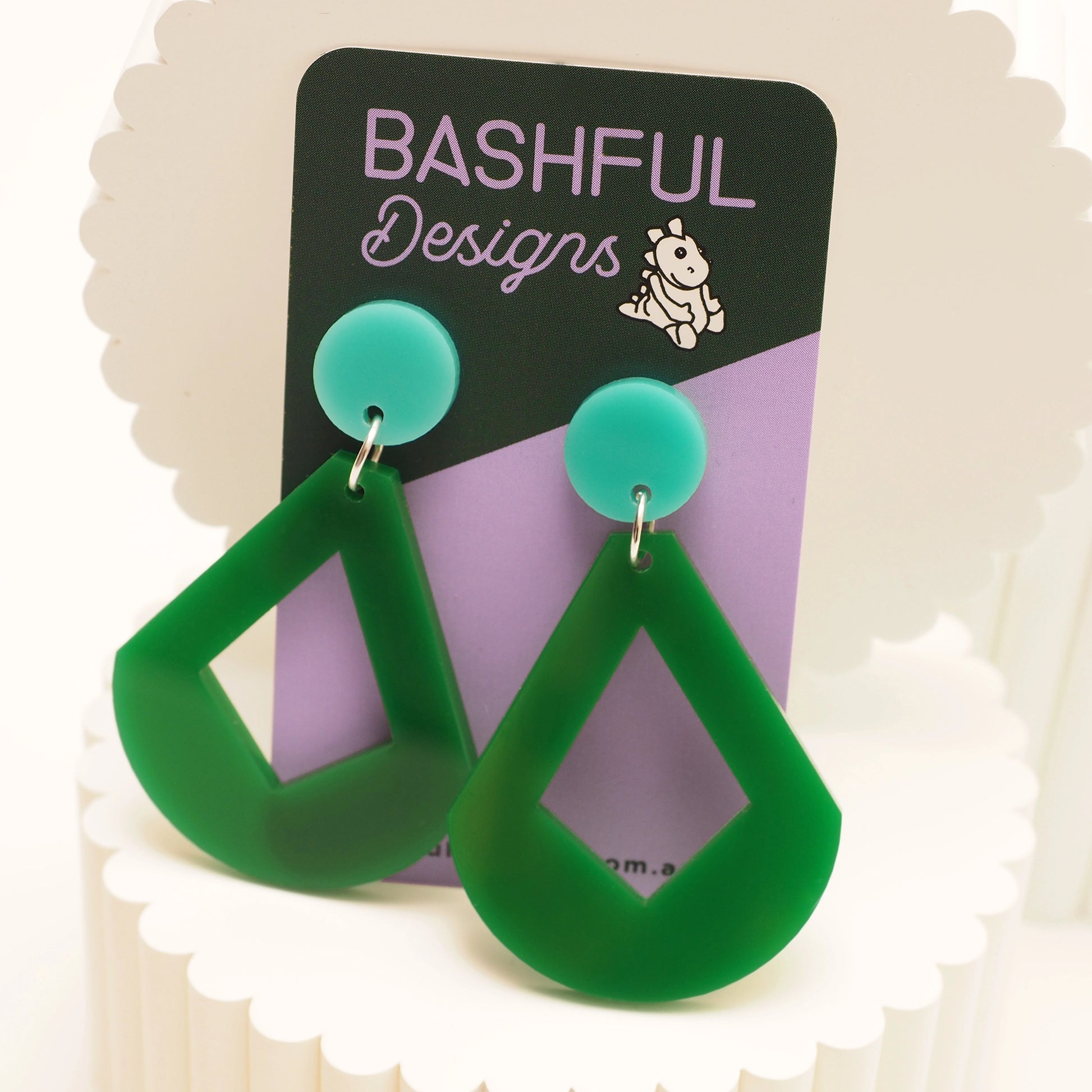 Green curved diamond shaped earrings, that feature a solid round aqua earring topper. These earrings are shown on a 'Bashful Designs' earring card.