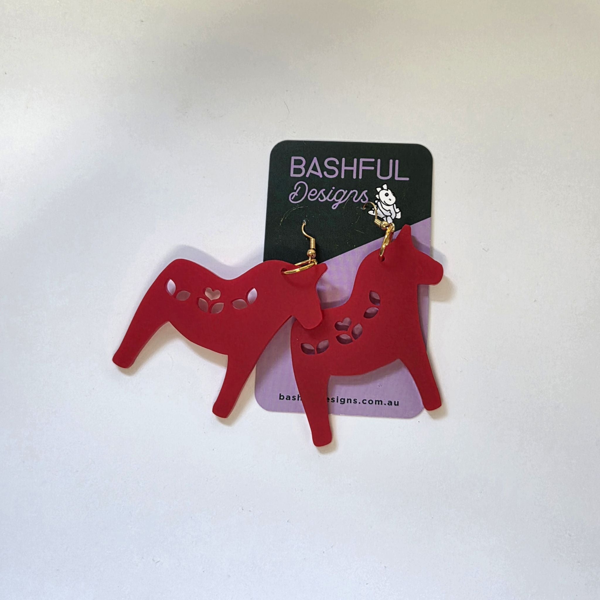 Earrings in a shape of a Nordic Christmas horse, made in red acrylic.