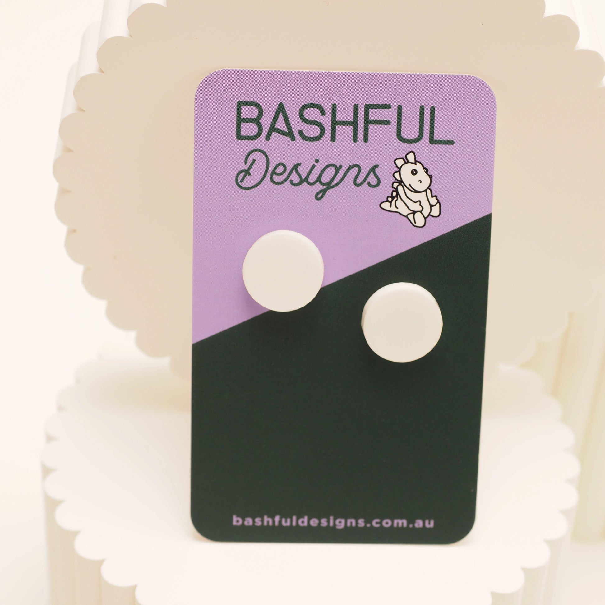 White dot stud earrings on a 'Bashful Designs' branded card.