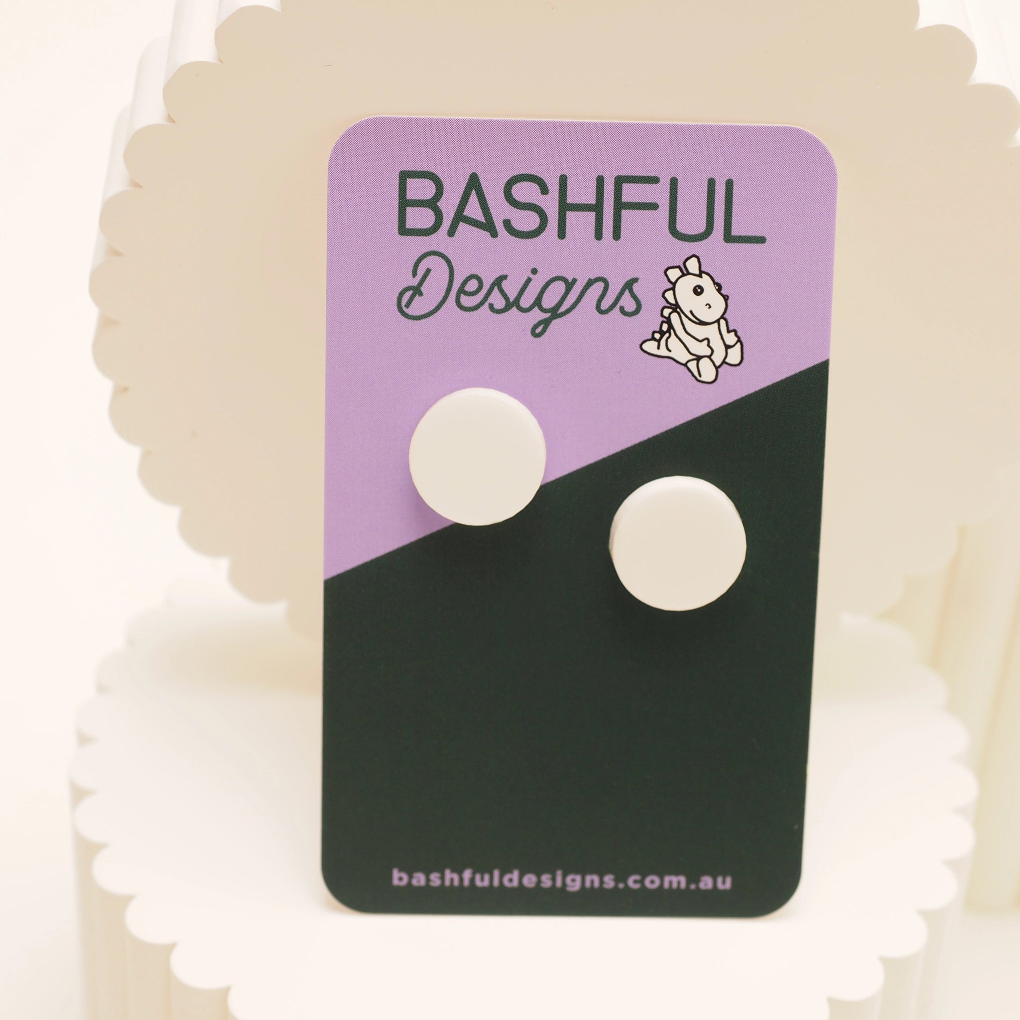 White dot stud earrings on a 'Bashful Designs' branded card.